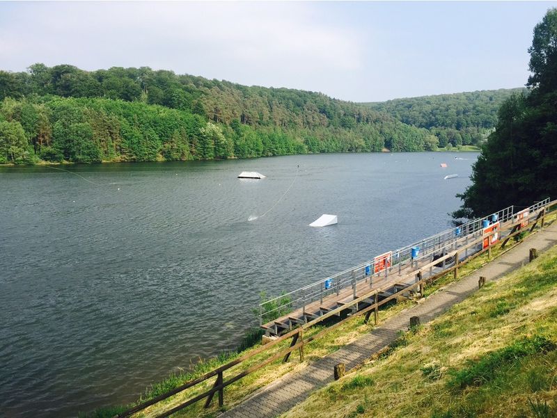 Blick über den Twistesee auf Wakeboard-Rampen im Wasser und einen Holzsteg am Ufer