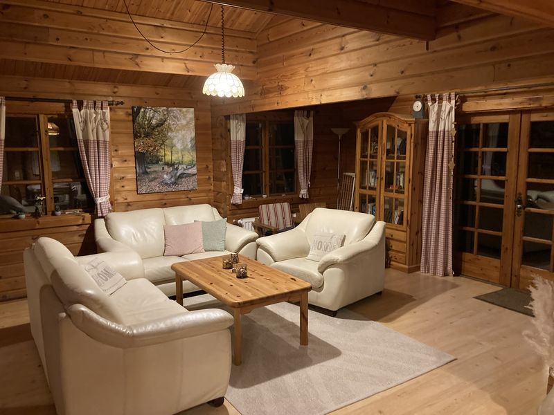 Gemütliches Wohnzimmer mit hellen Ledersofas, Holzwänden und Couchtisch