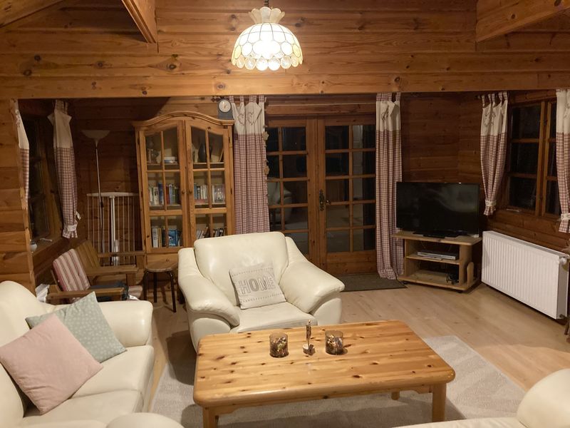 Wohnzimmer mit Fernseher, Vitrinenschrank und Terrassentür